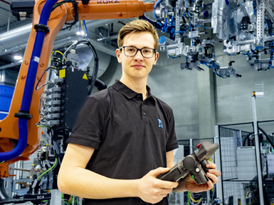 Ein junger Mitarbeiter der EBZ arbeitet mit einem Industrieroboter.