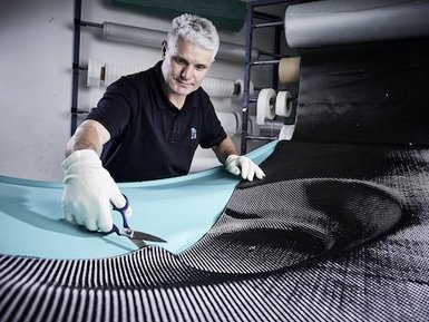Ein Mitarbeiter der EBZ Gruppe arbeitet an einem Serienbauteil aus faserverstärktem Kunststoff.