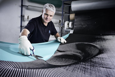 An employee of the EBZ Group is working on a serial component made of fiber-reinforced plastics.