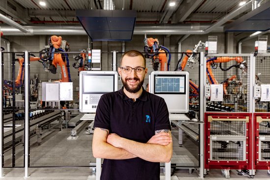 A dual student stands in front of a robot system.