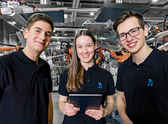 Drei Auszubildende der EBZ Gruppe sind vor Industrierobotern abgebildet. Ausbildung 4.0 – Digitalisierung wird in der Ausbildung  bei EBZ groß geschrieben. 